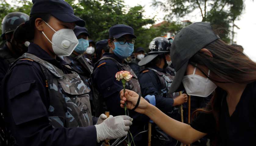 A protester greets as she offers flower to the riot police personnel during a protest against govern