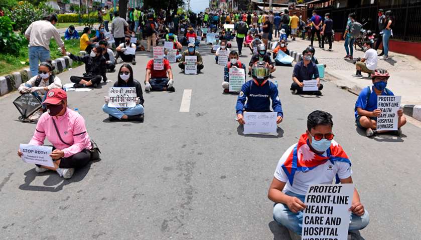 Protesters maintaining social distancing hold placards during a demonstration against the government