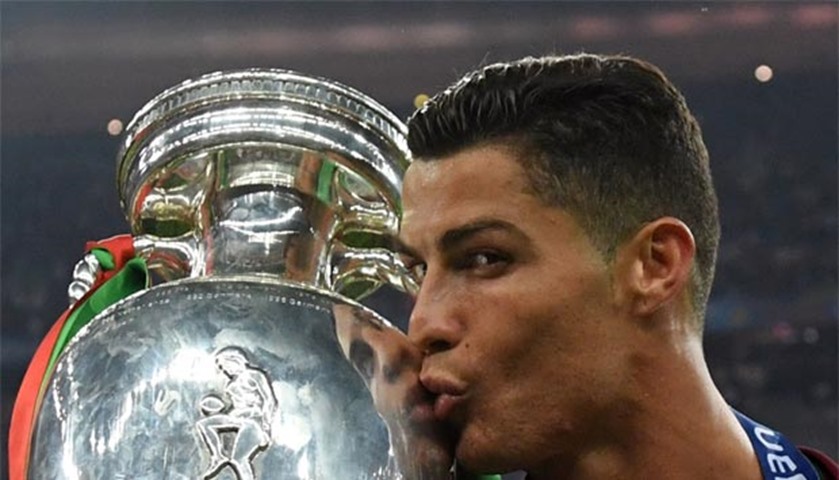 Cristiano Ronaldo kisses the trophy while posing on the pitch after Portugal won the Euro 2016 final