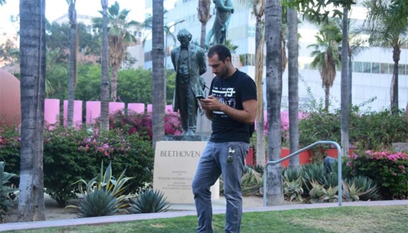 Kaylen Ray looks at his phone while playing Pokemon Go before a statue of Beethoven in Los Angeles
