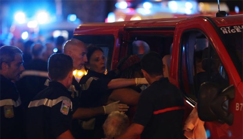Rescue workers help injured people to get in an ambulance after a truck drove into a crowd in Nice