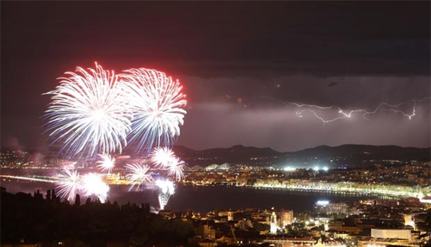 A flash of lightning as fireworks explode over Nice as part of the Bastille Day celebrations
