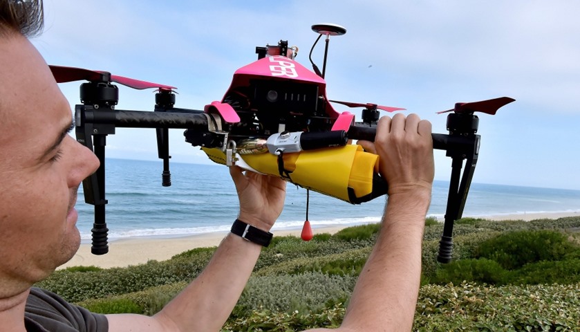 A technician checking Helper, the surveillance drone,  carrying  a life buoy