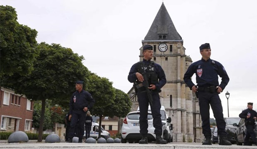 French CRS police stand guard in front of the church a day after a hostage-taking killed a priest