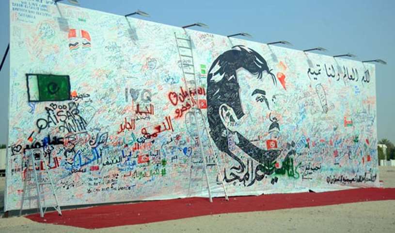 A billboard with a portrait of His Highness the Emir is covered with messages