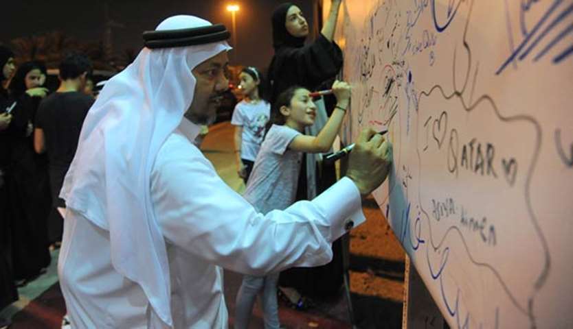 Qataris writing messages of solidarity on a billboard