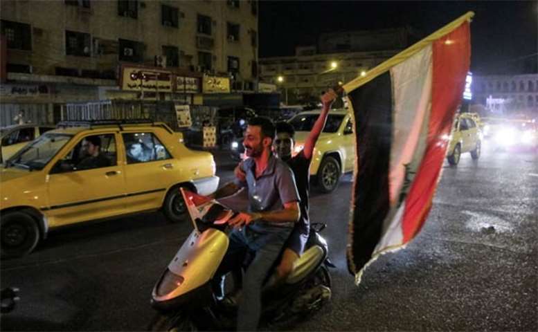 An Iraqi waves a national flag while celebrating at the Tahrir Square in Baghdad