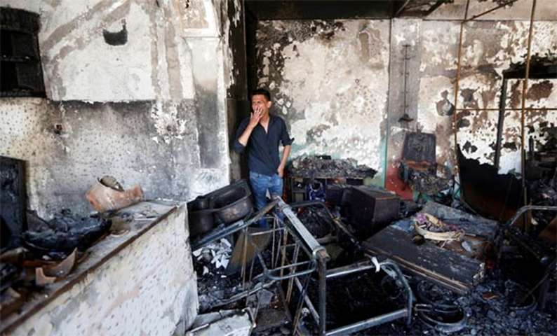 An Afghan shopkeeper smokes as he inspects his shop after a suicide attack