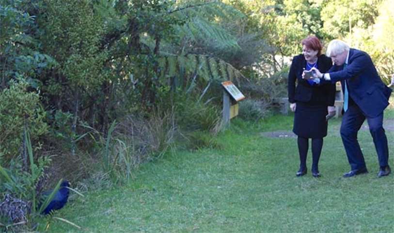 Boris Johnson takes a photograph of a bird during a visit to Zealandia on Tuesday