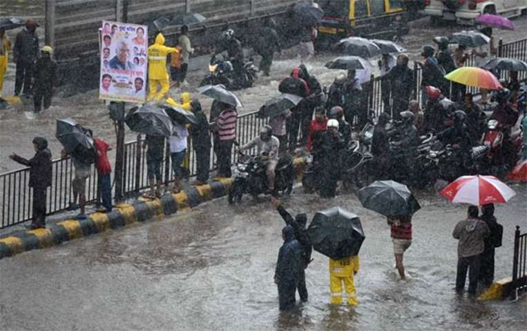 People stranded by flooding stand on a street in Mumbai