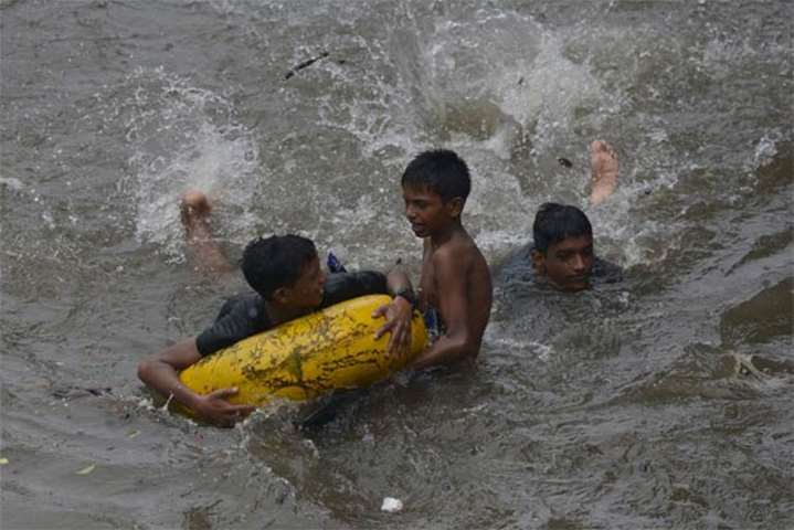 Children play on a flooded street during heavy rain in Mumbai