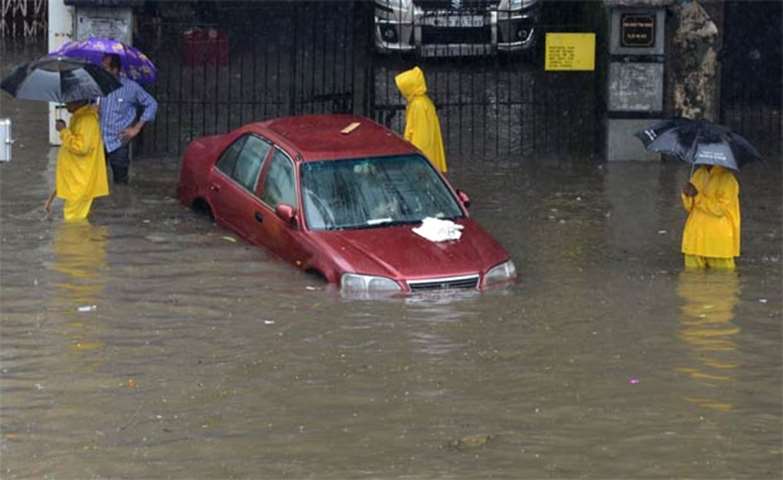 A vehicle lies submerged as people gather around it in Mumbai
