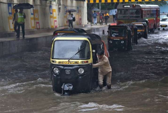 A man pushes his auto-rickshaw through a water-logged underpass after heavy rain in Mumbai