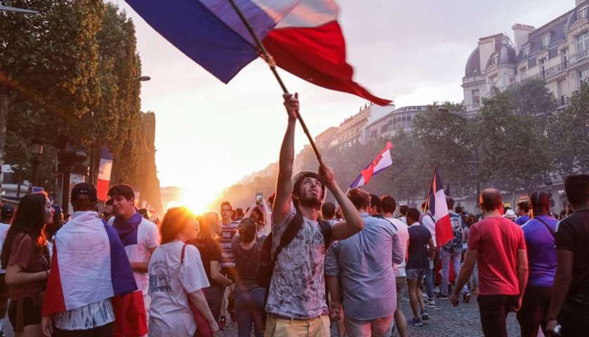 A man waves a French flag as people celebrate France\'s victory
