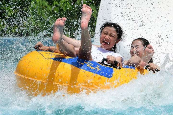 Youngsters react during splashdown as they enjoy a ride down a water slide in Tokyo