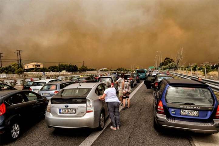 Cars are blocked at the closed National Road during a wildfire in Kineta, near Athens