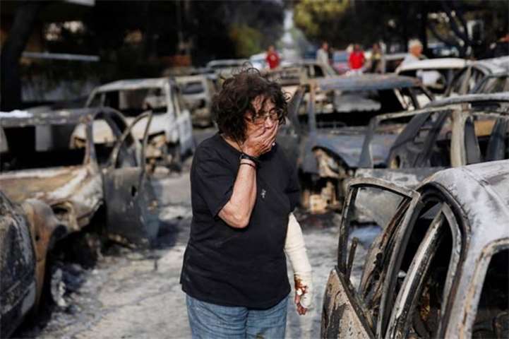 A woman reacts as she tries to find her dog following a wildfire in Mati on Tuesday