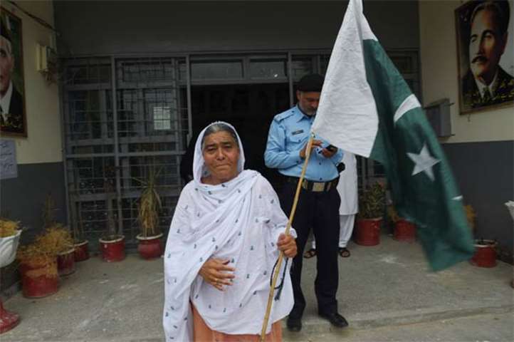 A woman holds Pakistan\'s national flag after casting her ballot in Rawalpindi