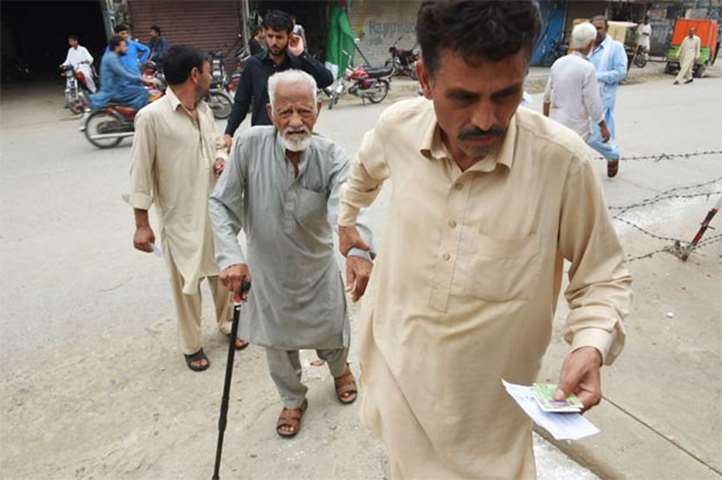 An elderly man is assisted by his son as they arrive at a polling station in Rawalpindi