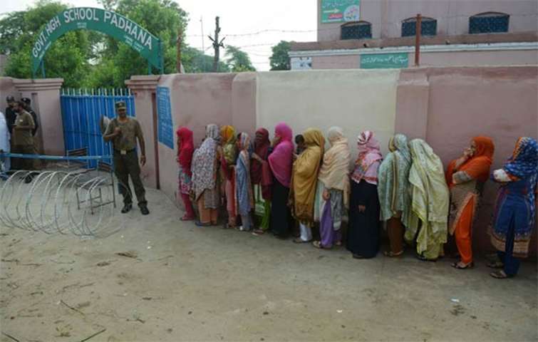 Women stand in a queue as they wait to cast their vote in Lahore on Wednesday