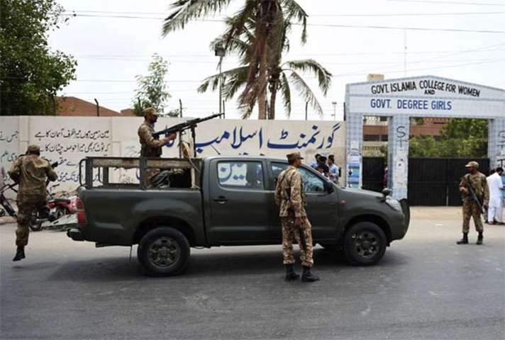 Pakistani soldiers stand guard outside a polling station in Karachi
