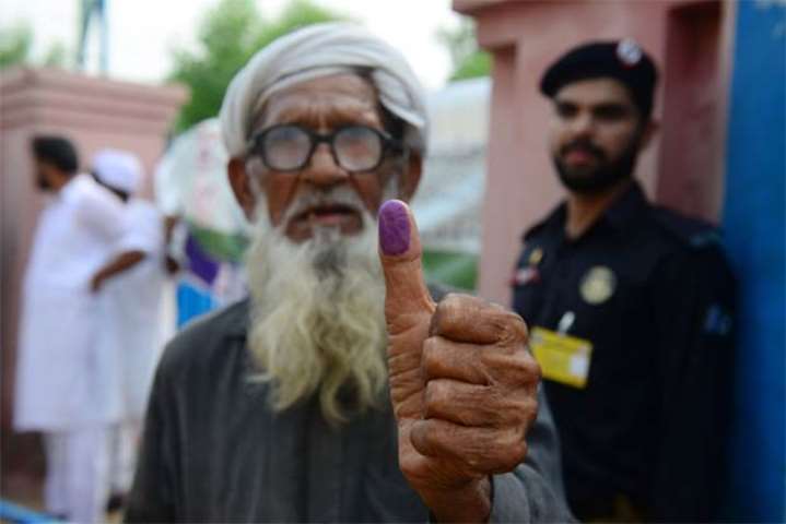 An elderly Pakistani man shows his inked thump after casting his ballot in Lahore