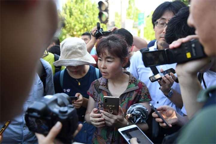 A woman speaks to journalists at the scene of an explosion in Beijing before being dragged away