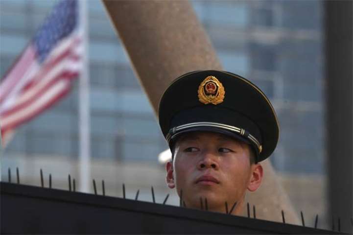 A paramilitary policeman looks on past the US flag in Beijing following a blast