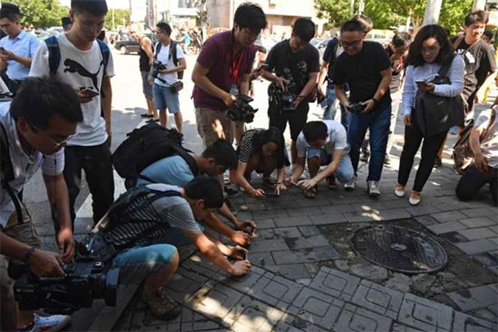 People take photos of scattered glass and blood on the pavement outside the US embassy compound