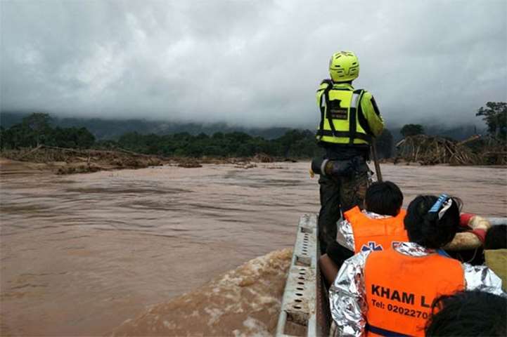 A Thai rescuer riding in a raft with survivors close to the swollen river in Attapeu province