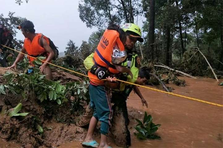 A Thai rescuer carrying a young flood survivor close to the swollen river in Attapeu province