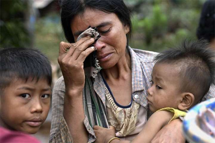 A woman carries a child in the flood ravaged village in Sanamxai, Attapeu province