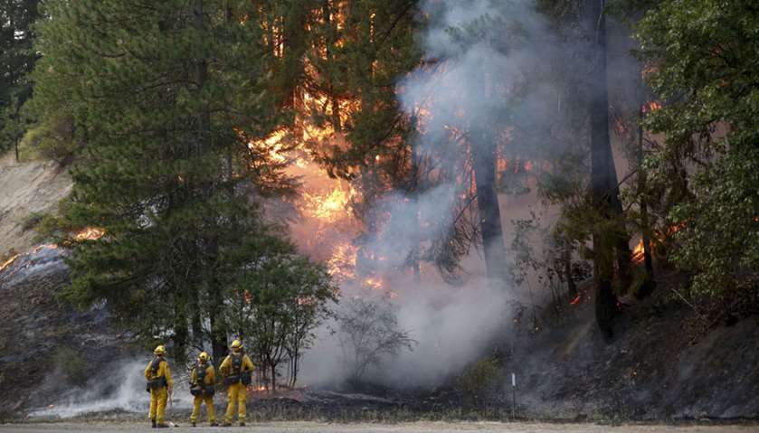 CalFire firefighters monitor flames above State Highway 299 while battling the Carr Fire
