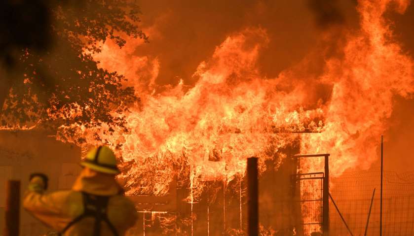 A firefighter watches as a building burns during the Mendocino Complex fire in Lakeport, California