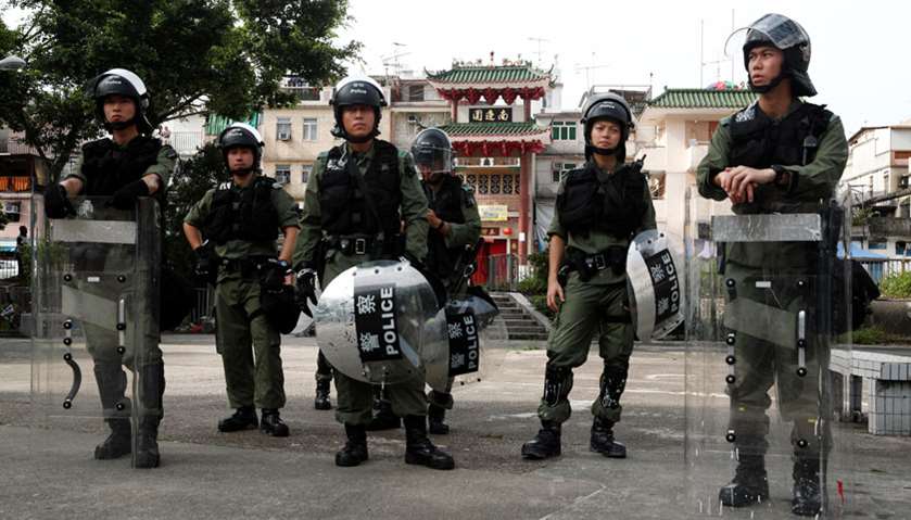Police officers stand guard outside Nam Pin Wai village during a protest against the Yuen Long attac