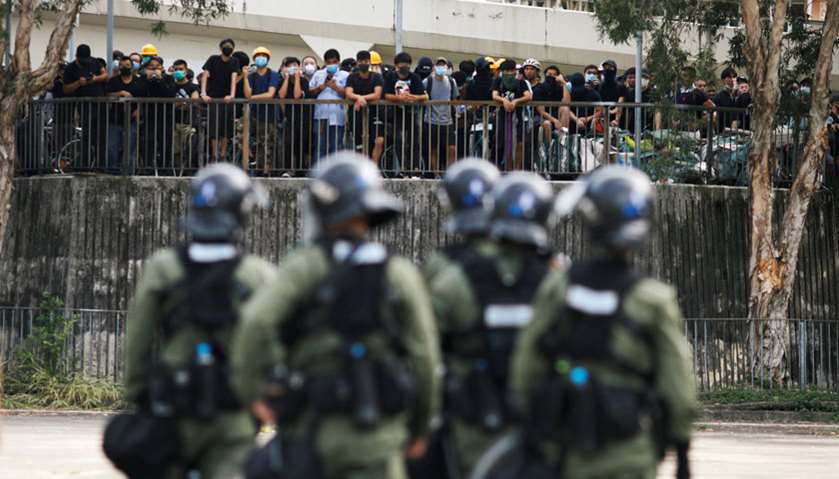 Police officers stand guard outside Nam Pin Wai village during a protest against the Yuen Long attac