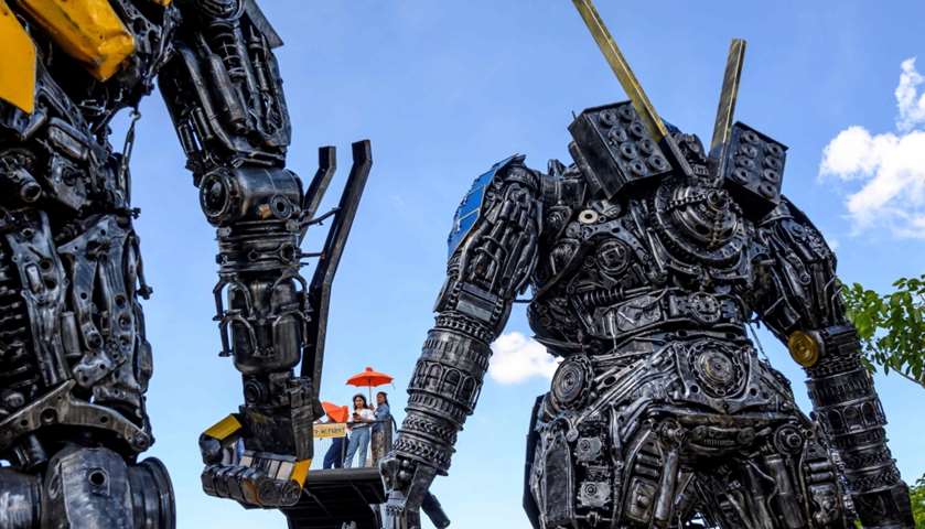 Tourists taking photos of life-sized sculptures of characters from the \"Transformers\" film franchise