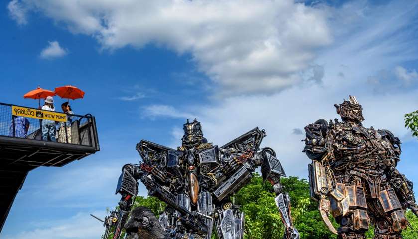Tourists taking photos of life-sized sculptures of characters from \"Transformers\" film