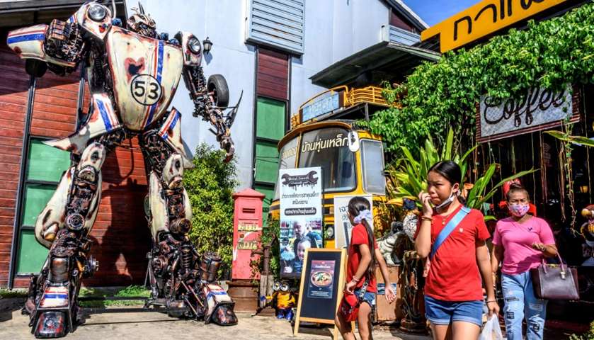 Tourists walking in front of a life-sized sculpture of a character from the \"Transformers\" film fran