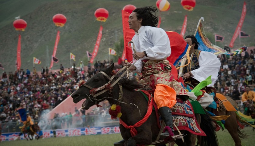 Ethnic Tibetans ride horses in traditional dress, showing their skills