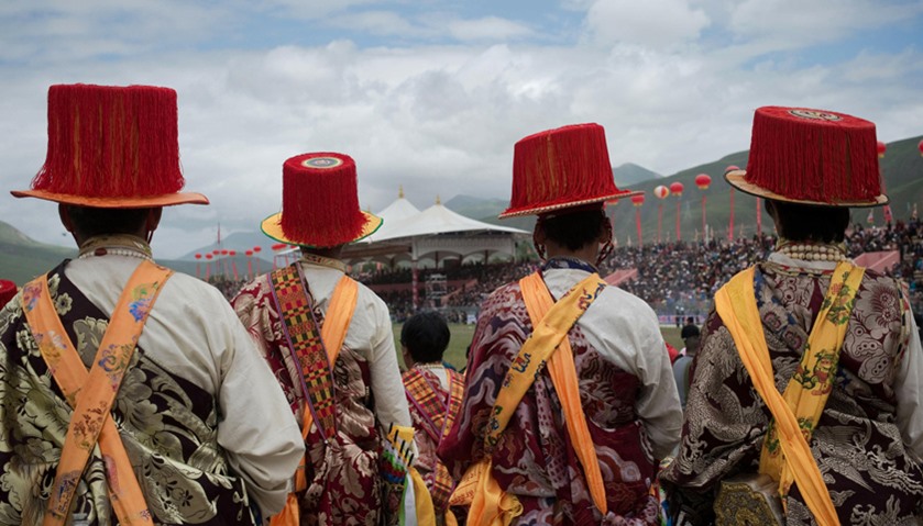 Ethnic Tibetans wearing traditional costumes stand waiting to perform