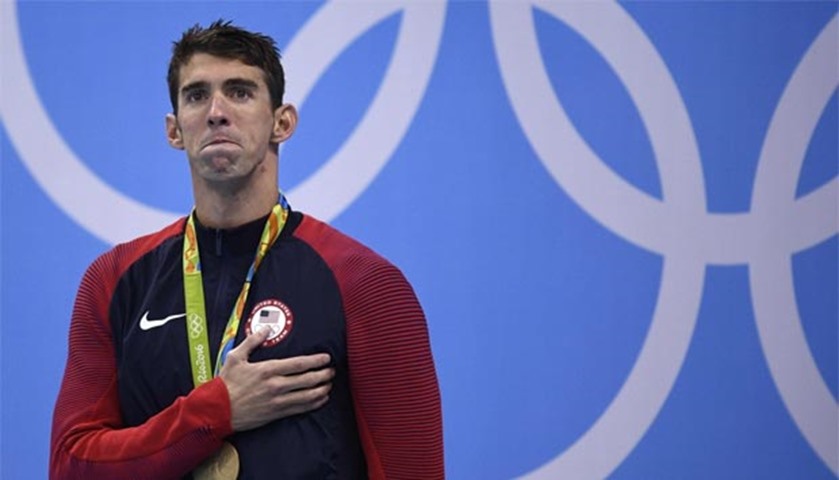 Gold medallist Michael Phelps listens to the US national anthem after his victory