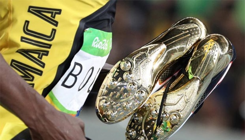 The Jamaican sprinter carries his shoes after winning the gold medal