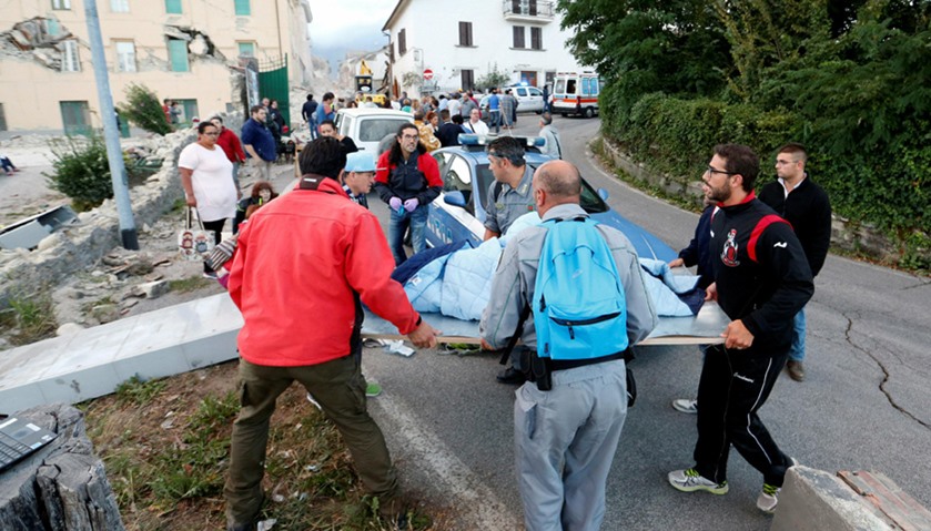 People stand along the road following a quake in Amatrice, central Italy