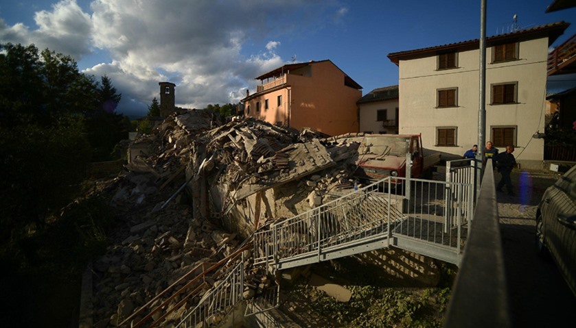 Residents walk past damaged buildings after a strong heartquake