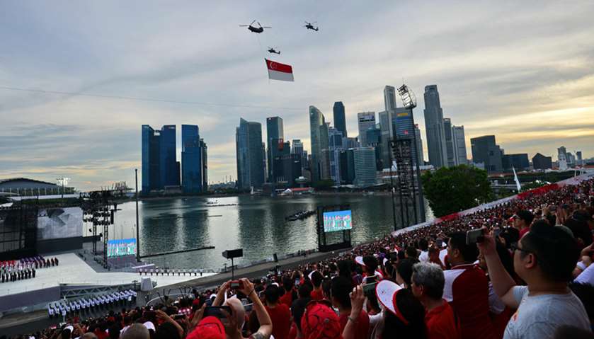 Republic of Singapore Air Force helicopters perform a flypast with a giant national flag