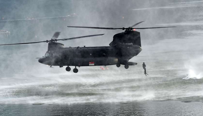 A Singaporean navy diver jumps out from a low flying Chinook helicopter