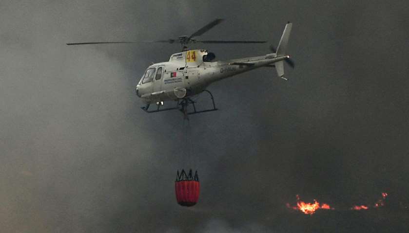 A firefighter helicopter flies over a wildfire following a new rash of forest fires