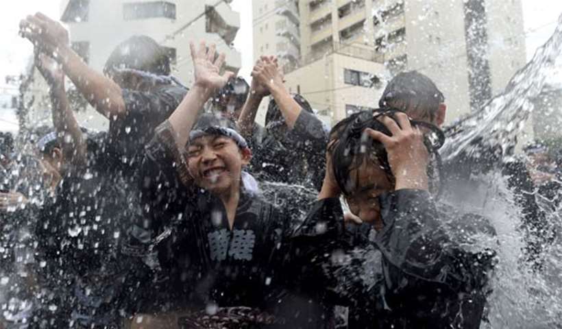 Residents carrying a portable shrine are splashed with water in Tokyo on Sunday