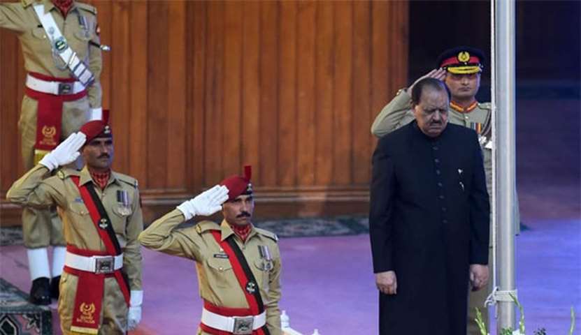 President Mamnoon Hussain stands as the national anthem is played after hoisting the national flag
